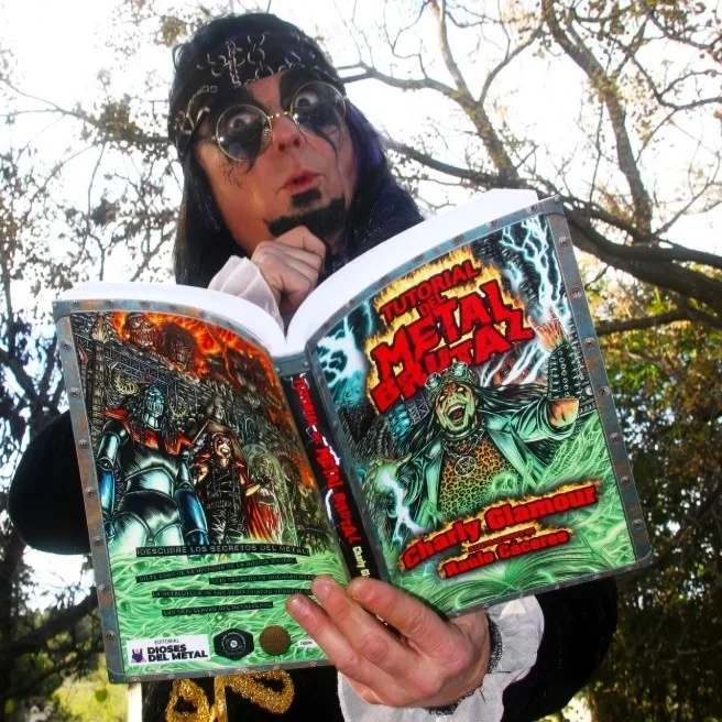Fotografía del cantante de música Heavy Charly Glamour, con su peculiar estilo, y con su libro 'Tutorial de MEtal Brutal', ilustrado por Raulo Cáceres