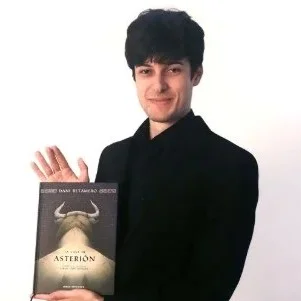 Fotografía del artista Dani Retamero con su libro ilustrado, 'la casa de Asterión'