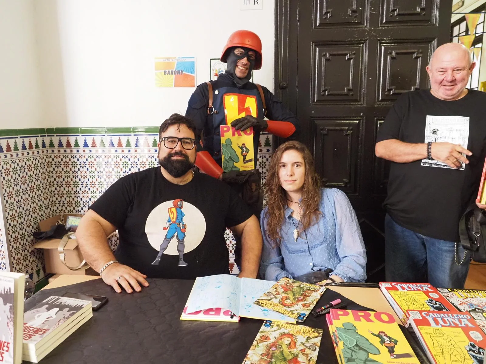 El creador del comic PRO David Galan Galindo, a la izquierda, y una de sus coloristas, Déborah Villahoz, a la derecha, en el stand con su comic. Detrás, Sergio haciendo cosplay del protagonista del comic