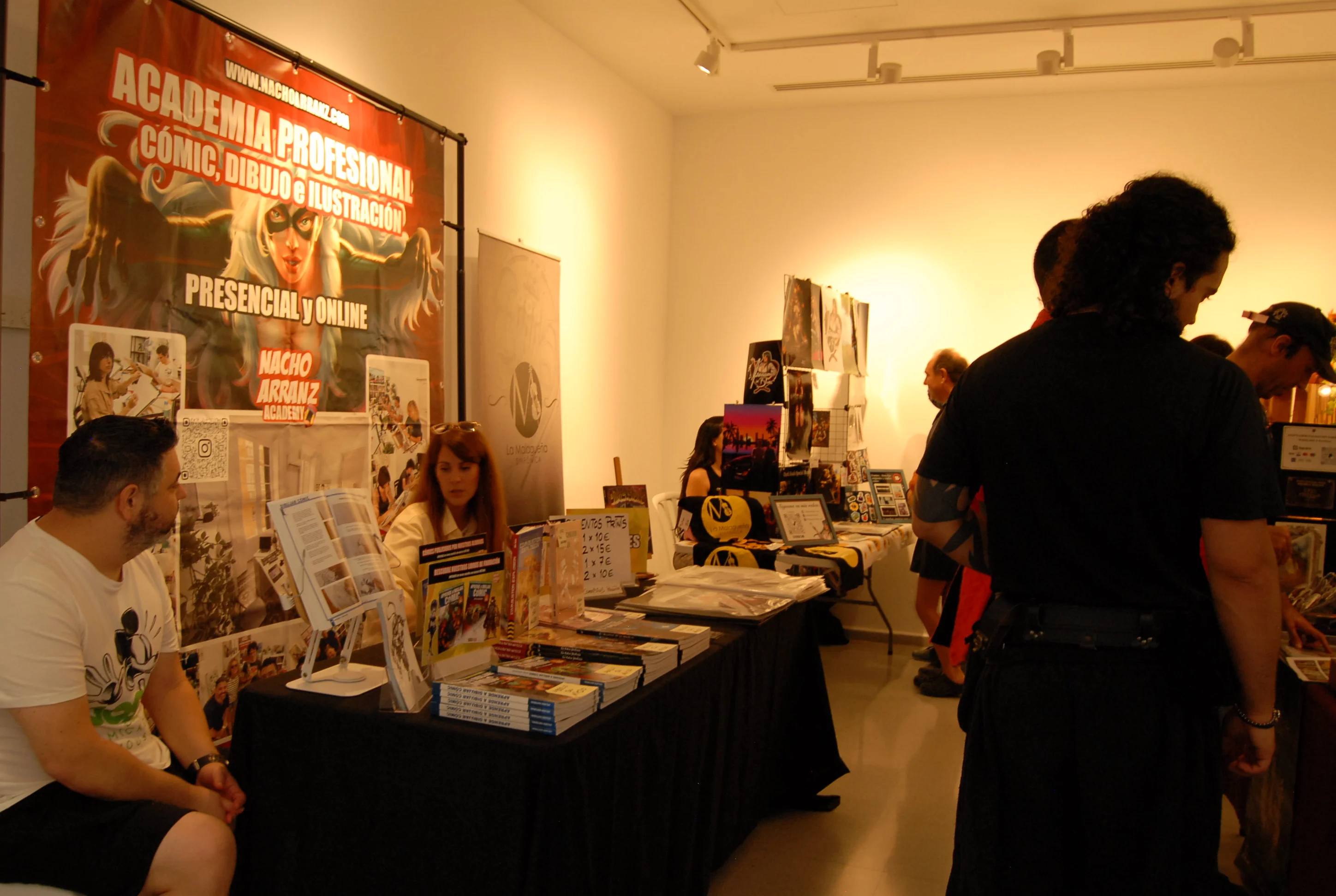 Pasillos de La Caja Blanca durante el evento de ImaginaMálaga, con los stands del dibujante e ilustrador Nacho Arranz y La Malagueña Sinfónica con la ilustradora digital Izanami In Blue al fondo